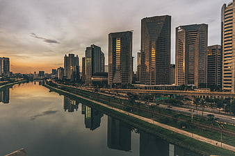 Modern city skyline with skyscrapers reflecting in river at sunset
