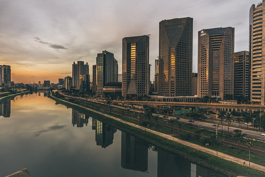 Modern city skyline with skyscrapers reflecting in river at sunset