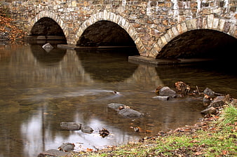 Old stone bridge over calm river in autumn