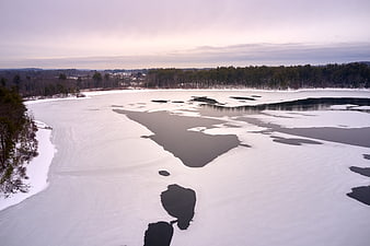 Aerial view of partially frozen lake in winter landscape