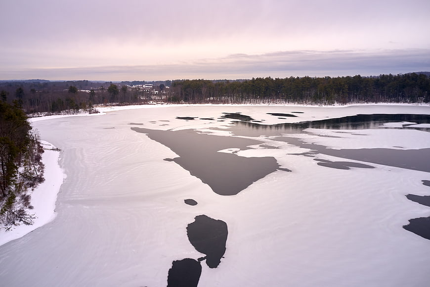 Aerial view of partially frozen lake in winter landscape