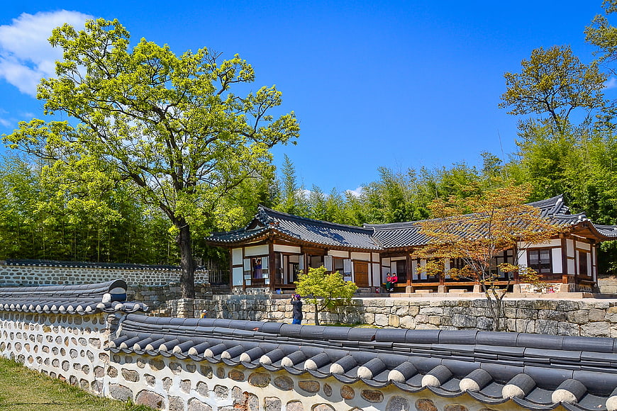 Traditional Korean Hanok Village With Stone Walls And Blue Sky