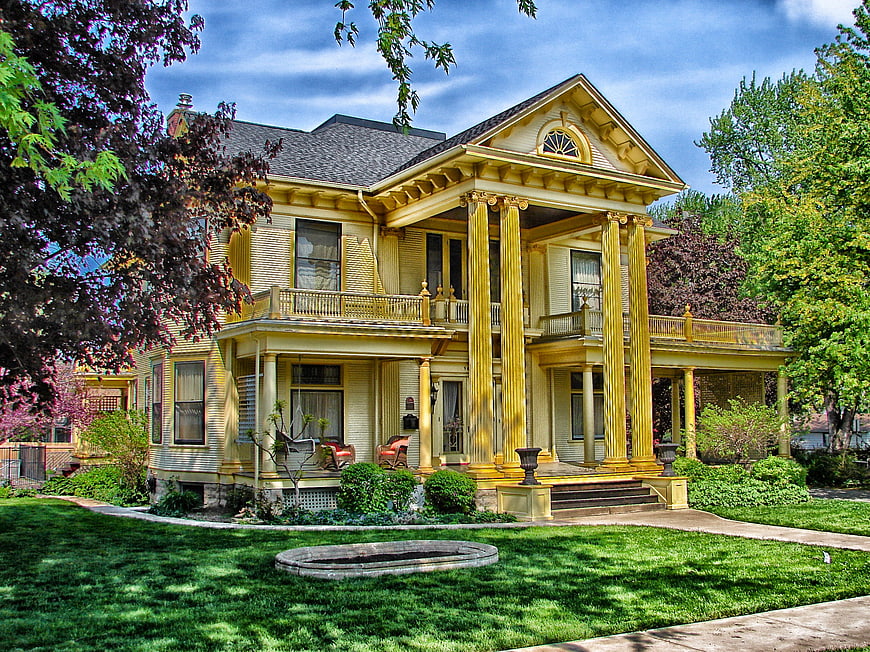 Grand Yellow Victorian House with Columns and Green Lawn