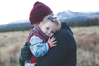 Mother holding toddler daughter in mountain field