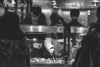 Black and white photo of people serving food at a buffet