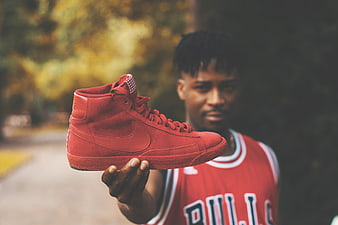 Man holding red high-top sneaker outdoors