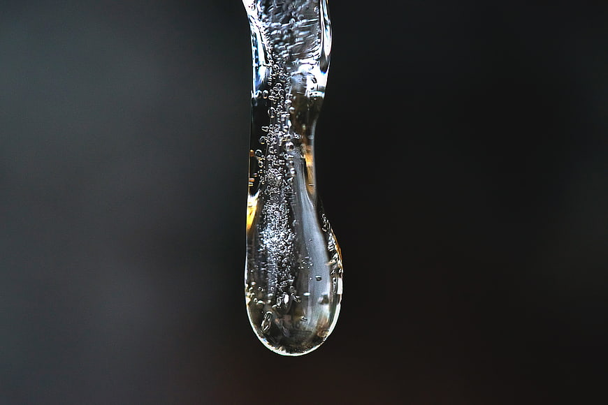 Macro shot of a clear icicle with bubbles on dark background