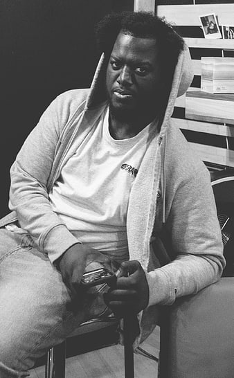 Black and white portrait of a man in a hoodie holding a phone
