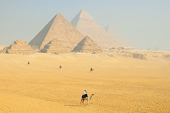 Camel riders in the desert with Giza Pyramids in background