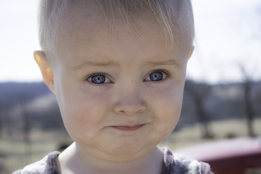 Close-up portrait of a toddler with blue eyes outdoors