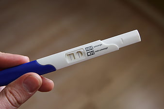 Close-up of hand holding positive pregnancy test stick