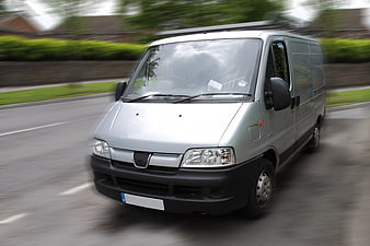 Silver delivery van driving fast on suburban road