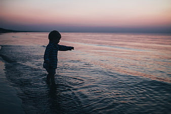 Toddler Boy Playing in Ocean Waves at Sunset