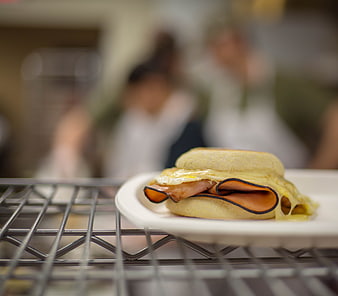 Close-up of breakfast sandwich with egg, ham, and cheese on a wire rack