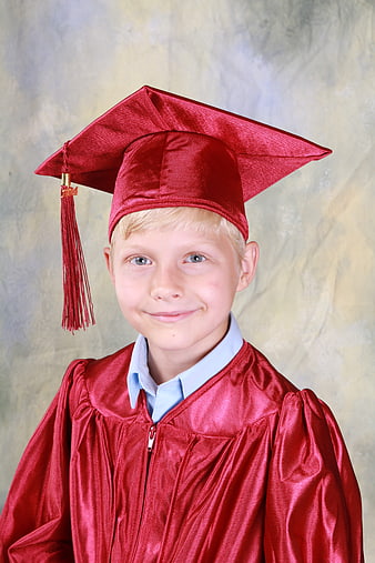 Happy young boy in red graduation cap and gown