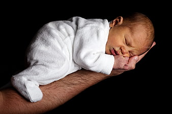 Sleeping newborn baby wrapped in white towel held in father's hands