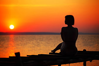 Silhouette of Woman Watching Sunset Over Ocean