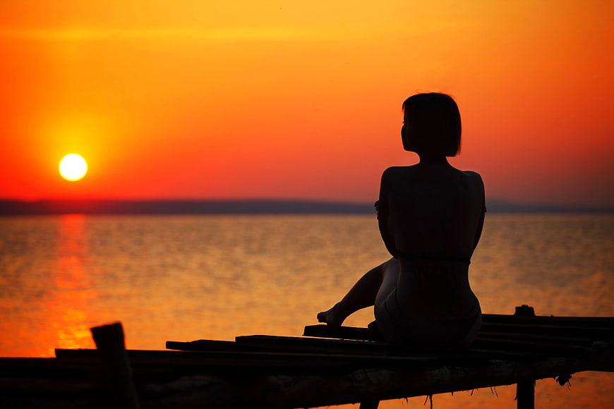 Silhouette of Woman Watching Sunset Over Ocean