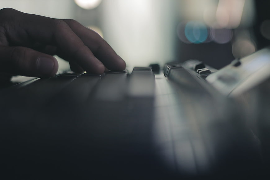 Close-up of hand typing on dark computer keyboard