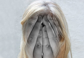 Blonde Woman Covering Face With Hands Against Gray Background