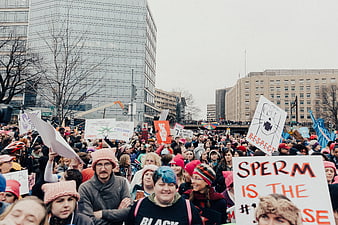 Crowd at urban protest rally holding signs and wearing pink hats