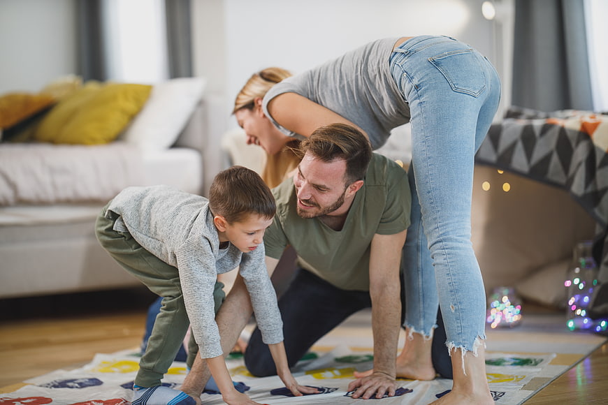 Happy family playing Twister game on living room floor