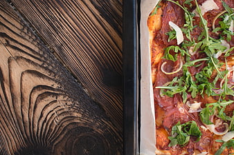 Top view of homemade pizza with arugula on wooden table