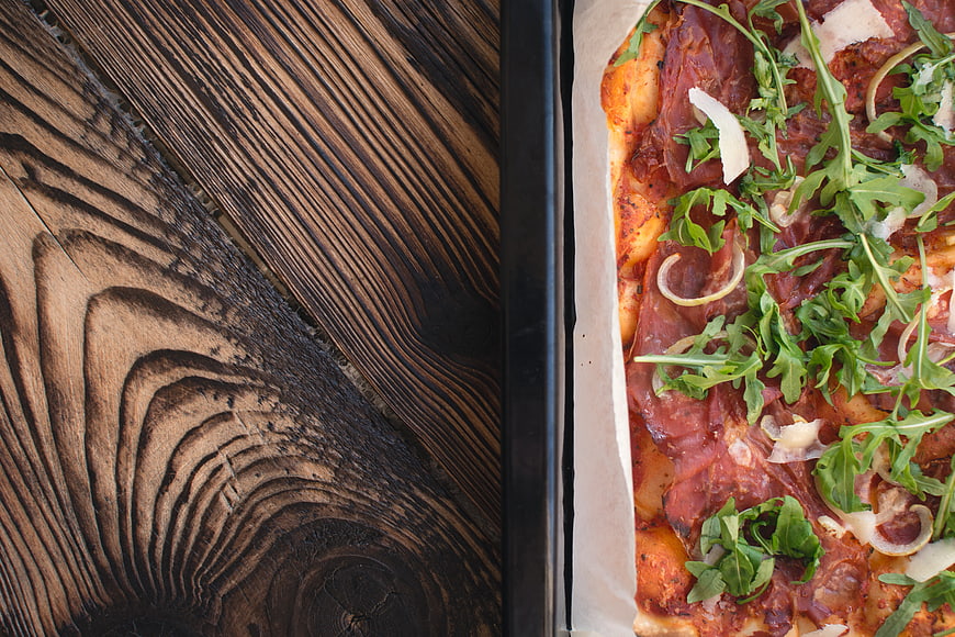 Top view of homemade pizza with arugula on wooden table