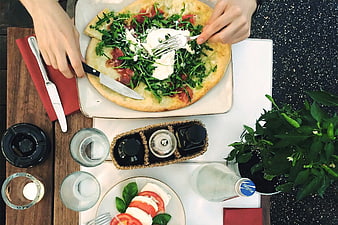 Overhead view of fresh pizza with arugula and burrata being cut