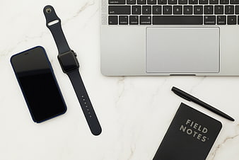 Flat lay of laptop, smartphone, smartwatch, and notebook on marble