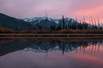 Serene mountain reflection in lake at sunset with pink sky