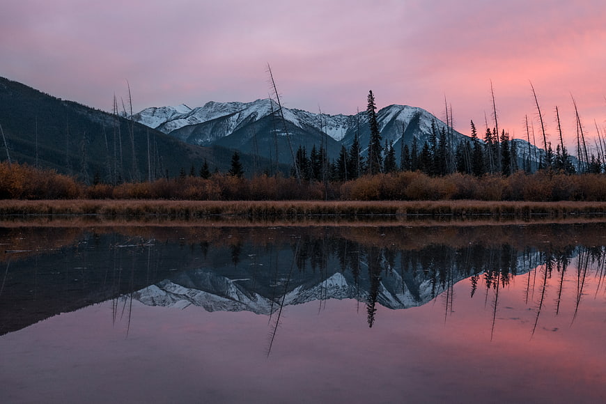 Serene mountain reflection in lake at sunset with pink sky