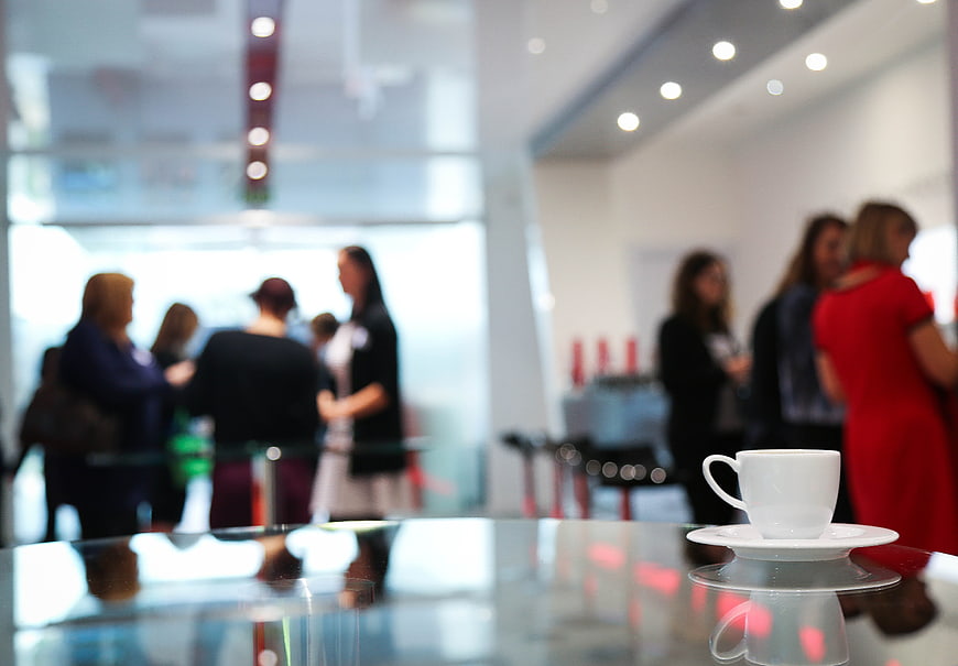 White coffee cup on glass table with blurred business meeting background