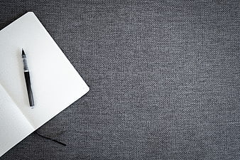 Minimalist notebook and pen on textured gray background