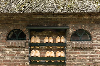 Traditional wooden clogs on a brick wall with thatched roof
