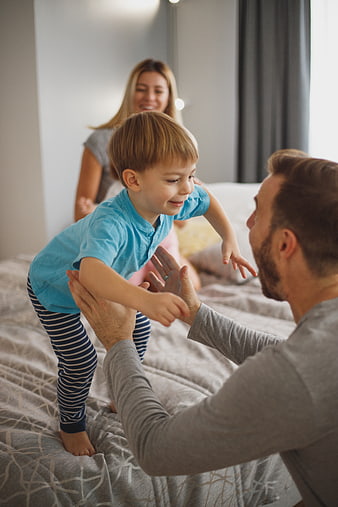 Happy family playing on bed with jumping child