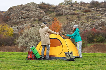 Couple Setting Up Yellow Camping Tent in Autumn Nature