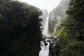 Majestic waterfall cascading through misty forest canyon