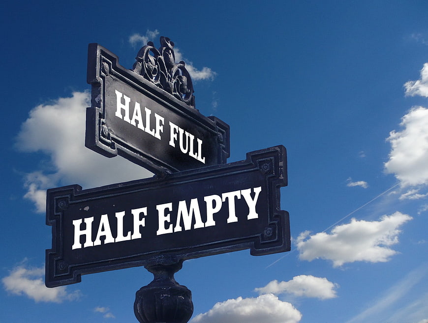 Half Full Half Empty Street Sign Against Blue Sky