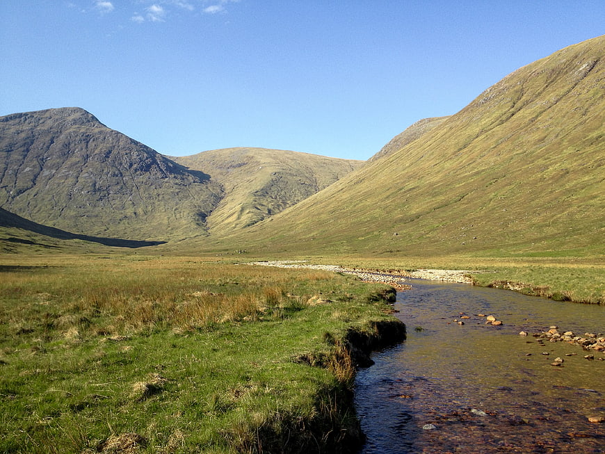 Scenic Mountain Valley with Flowing Stream and Green Hills