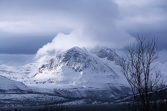 Snow-Capped Mountain Peak Under Dramatic Winter Clouds