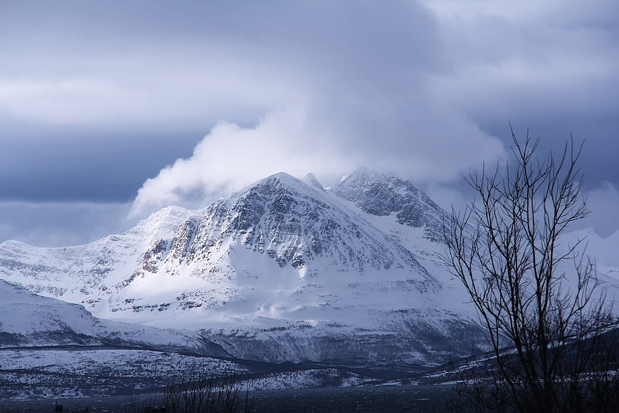 Snow-Capped Mountain Peak Under Dramatic Winter Clouds