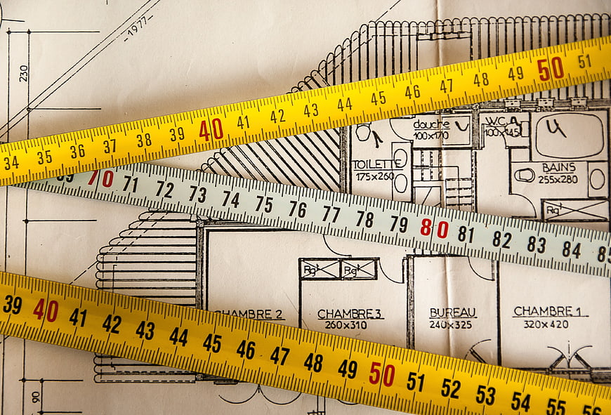 Measuring tapes on architectural blueprint floor plan