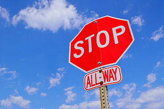 Red Stop Sign Against Blue Sky with Clouds