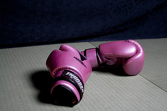 Pink boxing gloves on wooden floor with dark background