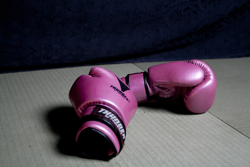 Pink boxing gloves on wooden floor with dark background