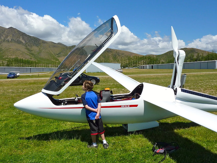 Young Boy Looking at White Ultralight Aircraft on Airfield