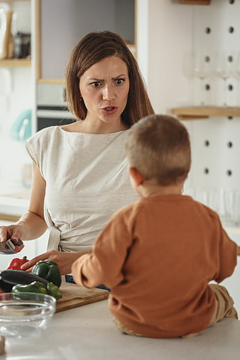 Angry mother scolding toddler in kitchen