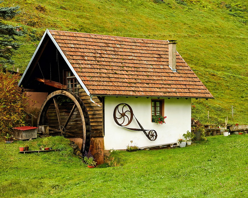 Traditional Water Mill with Wheel in Green Alpine Landscape