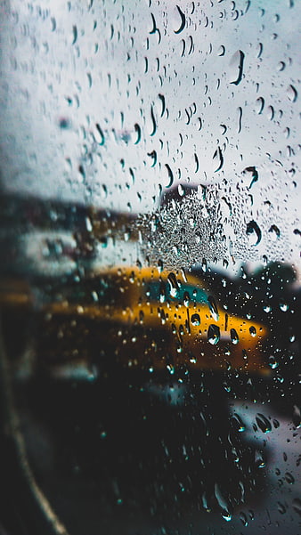 Raindrops on Window with Blurred Yellow Bus Background